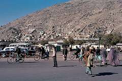 The bus station of Kabul, where buses to Kandahar and Herat leave from. There are Russian-built Volga taxis and two women in the all-enveloping “burqa” crossing the street.