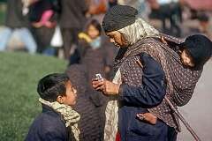 A boy and a woman carrying her child on the street in Mashhad.