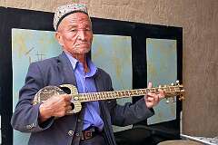Bezeklik, Xinjiang-Uyghur, China, 2011 - An Uyghur man playing a Kashgar “rawap”, at the Bezeklik Thousand Buddha Caves.
